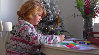 Noel Baba 'ya yeni yıl tatili için mektup yazan çocuk, rahat Noel süslemeleri ve ışıkları, renkli kalemler çizen kız, Noel Baba' ya hediyeler hazırlayan çocuk,