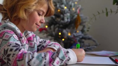 Noel Baba 'ya yeni yıl tatili için mektup yazan çocuk, rahat Noel süslemeleri ve ışıkları, renkli kalemler çizen kız, Noel Baba' ya hediyeler hazırlayan çocuk,