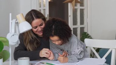 Kafkasyalı anne ve Afrikalı Amerikalı kız evde çalışıyor, rahat beyaz odada ödev yapıyor. Ebeveyn öğretmenliği, çocuk okulu kızı bilgi öğrenme, egzersiz kitabı yazma. Çocuklar için eğitim