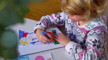 Noel Baba 'ya yeni yıl tatili için mektup yazan çocuk, rahat Noel süslemeleri ve ışıkları, renkli kalemler çizen kız, Noel Baba' ya hediyeler hazırlayan çocuk,