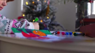 Noel Baba 'ya yeni yıl tatili için mektup yazan çocuk, rahat Noel süslemeleri ve ışıkları, renkli kalemler çizen kız, Noel Baba' ya hediyeler hazırlayan çocuk,