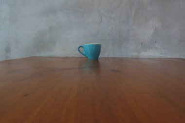 Kafedeki ahşap masada mavi bardakta kahve.    