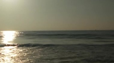 Sabahın erken saatlerinde deniz kıyısında, mavi dalgalar akıyor. Renkli kış gündoğumu. Soğuk fırtınalı dalgalar ve Baltık Denizi üzerindeki bulutlar, yere vuran altın deniz dalgaları. Manzara okyanusu