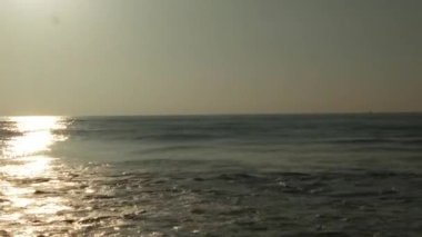 Sabahın erken saatlerinde deniz kıyısında, mavi dalgalar akıyor. Renkli kış gündoğumu. Soğuk fırtınalı dalgalar ve Baltık Denizi üzerindeki bulutlar, yere vuran altın deniz dalgaları. Manzara okyanusu