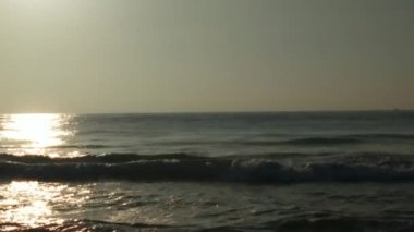 Sabahın erken saatlerinde deniz kıyısında, mavi dalgalar akıyor. Renkli kış gündoğumu. Soğuk fırtınalı dalgalar ve Baltık Denizi üzerindeki bulutlar, yere vuran altın deniz dalgaları. Manzara okyanusu