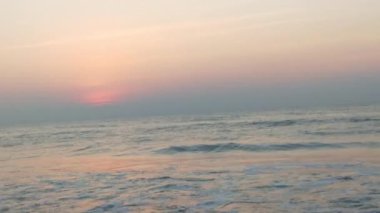 Sabahın erken saatlerinde deniz kıyısında, mavi dalgalar akıyor. Renkli kış gündoğumu. Soğuk fırtınalı dalgalar ve Baltık Denizi üzerindeki bulutlar, yere vuran altın deniz dalgaları. Manzara okyanusu