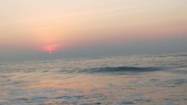 Sabahın erken saatlerinde deniz kıyısında, mavi dalgalar akıyor. Renkli kış gündoğumu. Soğuk fırtınalı dalgalar ve Baltık Denizi üzerindeki bulutlar, yere vuran altın deniz dalgaları. Manzara okyanusu