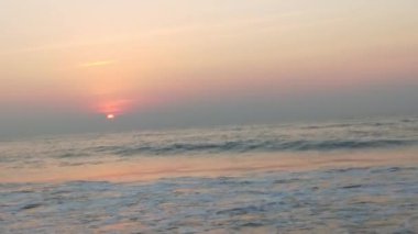 Sabahın erken saatlerinde deniz kıyısında, mavi dalgalar akıyor. Renkli kış gündoğumu. Soğuk fırtınalı dalgalar ve Baltık Denizi üzerindeki bulutlar, yere vuran altın deniz dalgaları. Manzara okyanusu