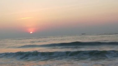 Sabahın erken saatlerinde deniz kıyısında, mavi dalgalar akıyor. Renkli kış gündoğumu. Soğuk fırtınalı dalgalar ve Baltık Denizi üzerindeki bulutlar, yere vuran altın deniz dalgaları. Manzara okyanusu