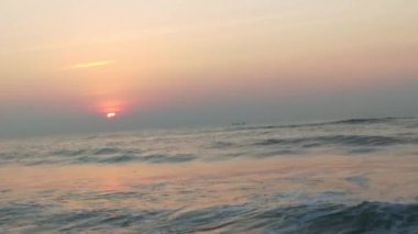 Sabahın erken saatlerinde deniz kıyısında, mavi dalgalar akıyor. Renkli kış gündoğumu. Soğuk fırtınalı dalgalar ve Baltık Denizi üzerindeki bulutlar, yere vuran altın deniz dalgaları. Manzara okyanusu