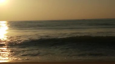 Sabahın erken saatlerinde deniz kıyısında, mavi dalgalar akıyor. Renkli kış gündoğumu. Soğuk fırtınalı dalgalar ve Baltık Denizi üzerindeki bulutlar, yere vuran altın deniz dalgaları. Manzara okyanusu