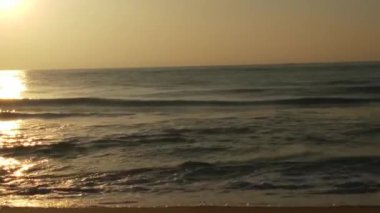 Sabahın erken saatlerinde deniz kıyısında, mavi dalgalar akıyor. Renkli kış gündoğumu. Soğuk fırtınalı dalgalar ve Baltık Denizi üzerindeki bulutlar, yere vuran altın deniz dalgaları. Manzara okyanusu