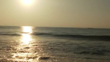 Sabahın erken saatlerinde deniz kıyısında, mavi dalgalar akıyor. Renkli kış gündoğumu. Soğuk fırtınalı dalgalar ve Baltık Denizi üzerindeki bulutlar, yere vuran altın deniz dalgaları. Manzara okyanusu