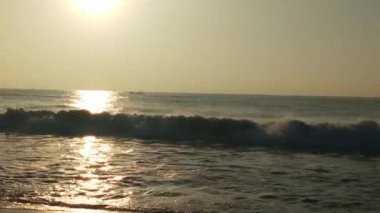 Sabahın erken saatlerinde deniz kıyısında, mavi dalgalar akıyor. Renkli kış gündoğumu. Soğuk fırtınalı dalgalar ve Baltık Denizi üzerindeki bulutlar, yere vuran altın deniz dalgaları. Manzara okyanusu