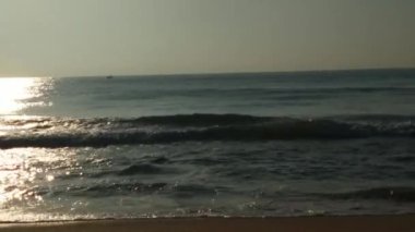 Sabahın erken saatlerinde deniz kıyısında, mavi dalgalar akıyor. Renkli kış gündoğumu. Soğuk fırtınalı dalgalar ve Baltık Denizi üzerindeki bulutlar, yere vuran altın deniz dalgaları. Manzara okyanusu