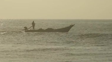 Güneşin doğuşunda balıkçıyla birlikte teknenin silueti Horizon Sunrise sahilinde güzel bir gün doğumu. Okyanus ve altın güneş doğuyor, parlak altın arka plan. Gün batımı. Gün batımında denizde balıkçı tekneleri. Balıkçı teknesinin gökyüzü silueti.. 