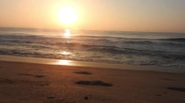 Horizon Sunrise plajında güzel bir gün doğumu. Okyanus ve altın güneş doğuyor, parlak altın arka plan. Güneşin batışında dramatik bulutlu gökyüzünün olduğu güzel manzara. Turuncu gün batımı, teknenin gölgesini denizdeki balıkçıyla vurdu. 