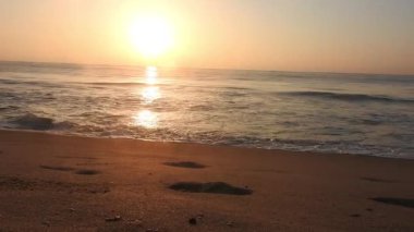 Horizon Sunrise plajında güzel bir gün doğumu. Okyanus ve altın güneş doğuyor, parlak altın arka plan. Güneşin batışında dramatik bulutlu gökyüzünün olduğu güzel manzara. Turuncu gün batımı, teknenin gölgesini denizdeki balıkçıyla vurdu. 