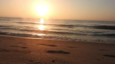 Horizon Sunrise plajında güzel bir gün doğumu. Okyanus ve altın güneş doğuyor, parlak altın arka plan. Güneşin batışında dramatik bulutlu gökyüzünün olduğu güzel manzara. Turuncu gün batımı, teknenin gölgesini denizdeki balıkçıyla vurdu. 