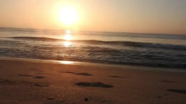 Horizon Sunrise plajında güzel bir gün doğumu. Okyanus ve altın güneş doğuyor, parlak altın arka plan. Güneşin batışında dramatik bulutlu gökyüzünün olduğu güzel manzara. Turuncu gün batımı, teknenin gölgesini denizdeki balıkçıyla vurdu. 