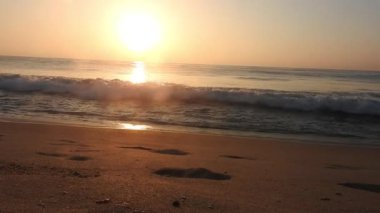 Horizon Sunrise plajında güzel bir gün doğumu. Okyanus ve altın güneş doğuyor, parlak altın arka plan. Güneşin batışında dramatik bulutlu gökyüzünün olduğu güzel manzara. Turuncu gün batımı, teknenin gölgesini denizdeki balıkçıyla vurdu. 