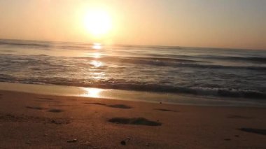 Horizon Sunrise plajında güzel bir gün doğumu. Okyanus ve altın güneş doğuyor, parlak altın arka plan. Güneşin batışında dramatik bulutlu gökyüzünün olduğu güzel manzara. Turuncu gün batımı, teknenin gölgesini denizdeki balıkçıyla vurdu. 