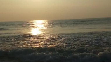 Sabahın erken saatlerinde deniz kıyısında, mavi dalgalar akıyor. Renkli kış gündoğumu. Soğuk fırtınalı dalgalar ve Baltık Denizi üzerindeki bulutlar, yere vuran altın deniz dalgaları. Okyanus manzarası dalgaları dalgalar dalgalar dalgalar deniz dalgaları