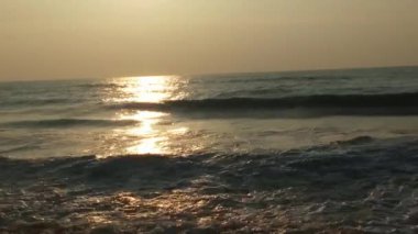 Sabahın erken saatlerinde deniz kıyısında, mavi dalgalar akıyor. Renkli kış gündoğumu. Soğuk fırtınalı dalgalar ve Baltık Denizi üzerindeki bulutlar, yere vuran altın deniz dalgaları. Okyanus manzarası dalgaları dalgalar dalgalar dalgalar deniz dalgaları