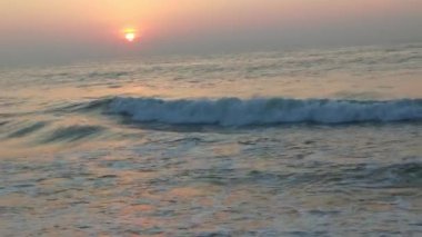 Sabahın erken saatlerinde deniz kıyısında, mavi dalgalar akıyor. Renkli kış gündoğumu. Soğuk fırtınalı dalgalar ve Baltık Denizi üzerindeki bulutlar, yere vuran altın deniz dalgaları. Okyanus manzarası dalgaları dalgalar dalgalar dalgalar deniz dalgaları