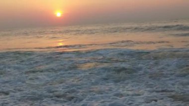 Sabahın erken saatlerinde deniz kıyısında, mavi dalgalar akıyor. Renkli kış gündoğumu. Soğuk fırtınalı dalgalar ve Baltık Denizi üzerindeki bulutlar, yere vuran altın deniz dalgaları. Okyanus manzarası dalgaları dalgalar dalgalar dalgalar deniz dalgaları