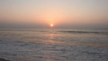Atlantik Okyanusu üzerinde gün doğumu, okyanus dalgaları bir manzara hareketi. Denizin ve doğanın kıyılarının videosu. Renkli kış gündoğumu. Soğuk fırtınalı dalgalar ve Baltık Denizi üzerindeki bulutlar manzara videosunda. Tropikal bir sahilde romantik bir gün doğumu.  