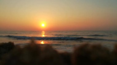 Dramatik deniz gündoğumu. Yanan gökyüzü ve parlayan altın dalgalar. Deniz batımı. Turuncu gökyüzünde deniz dalgaları ve arka planda güneş ışığı deniz suyu yüzeyinde parlıyor. Hiç kimse yok, tatil için güzel deniz manzarası, tatil, turistik temalar, gün doğumu