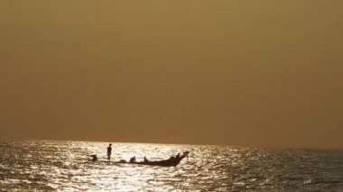 Balıkçı tekneleri eve dönüyor. Hindistan 'ın Odisha kentindeki Puri plajında güneş doğuyor. Doğayla güzel romantik bir manzara. Deniz sahilinde gün doğumunda balıkçı teknesiyle renkli bir gökyüzü. Dramatik deniz gündoğumu. Yanan gökyüzü ve parlayan dalgalar.