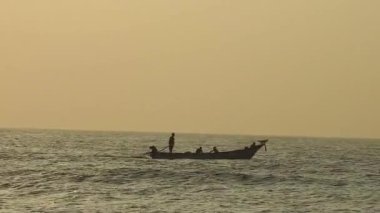 Balıkçı tekneleri eve dönüyor. Hindistan 'ın Odisha kentindeki Puri plajında güneş doğuyor. Doğayla güzel romantik bir manzara. Deniz sahilinde gün doğumunda balıkçı teknesiyle renkli bir gökyüzü. Dramatik deniz gündoğumu. Yanan gökyüzü ve parlayan dalgalar.