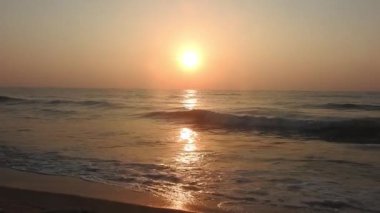 Dramatik deniz gündoğumu. Yanan gökyüzü ve parlayan altın dalgalar. Deniz üzerinde güzel bir gün batımı, sahile vuran okyanus dalgaları denizin üzerine vuran güneş. Plaj palmiyeleri adasında inanılmaz kırmızı gün doğumu. Turuncu renkler gündoğumu ve dalgalar. Doğa Gündoğumu 