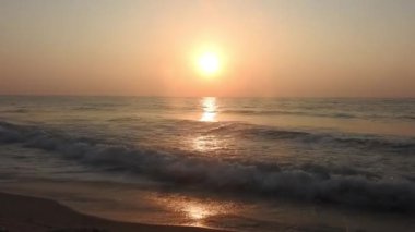 Dramatik deniz gündoğumu. Yanan gökyüzü ve parlayan altın dalgalar. Deniz üzerinde güzel bir gün batımı, sahile vuran okyanus dalgaları denizin üzerine vuran güneş. Plaj palmiyeleri adasında inanılmaz kırmızı gün doğumu. Turuncu renkler gündoğumu ve dalgalar. Doğa Gündoğumu 