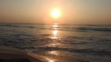 Sabahın erken saatlerinde deniz kıyısında, mavi dalgalar akıyor. Renkli kış gündoğumu. Soğuk fırtınalı dalgalar ve Baltık Denizi üzerindeki bulutlar, yere vuran altın deniz dalgaları. Manzara okyanus güzel manzara deniz üzerinde gün batımı, sahilde okyanus dalgaları