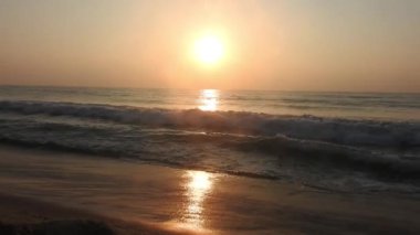 Sabahın erken saatlerinde deniz kıyısında, mavi dalgalar akıyor. Renkli kış gündoğumu. Soğuk fırtınalı dalgalar ve Baltık Denizi üzerindeki bulutlar, yere vuran altın deniz dalgaları. Manzara okyanus güzel manzara deniz üzerinde gün batımı, sahilde okyanus dalgaları