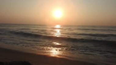 Sabahın erken saatlerinde deniz kıyısında, mavi dalgalar akıyor. Renkli kış gündoğumu. Soğuk fırtınalı dalgalar ve Baltık Denizi üzerindeki bulutlar, yere vuran altın deniz dalgaları. Manzara okyanus güzel manzara deniz üzerinde gün batımı, sahilde okyanus dalgaları