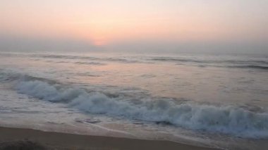 Sabahın erken saatlerinde deniz kıyısında, mavi dalgalar akıyor. Renkli kış gündoğumu. Soğuk fırtınalı dalgalar ve Baltık Denizi üzerindeki bulutlar, yere vuran altın deniz dalgaları. Manzara okyanus güzel manzara deniz üzerinde gün batımı, sahilde okyanus dalgaları
