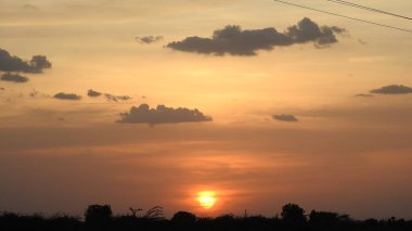 Gölde gün batımında insanların, ağaçların ve teknelerin silueti gün batımında bir arabanın üzerinde dans eden çocukların güzel silueti altın gökyüzü ve siluetli ağaçlar. Çocukların gölgesi parkta birlikte duruyor. Gün batımı gökyüzü ve ağaçlar manzarası.