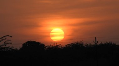 Gölde gün batımında insanların, ağaçların ve teknelerin silueti gün batımında bir arabanın üzerinde dans eden çocukların güzel silueti altın gökyüzü ve siluetli ağaçlar. Çocukların gölgesi parkta birlikte duruyor. Gün batımı gökyüzü ve ağaçlar manzarası.