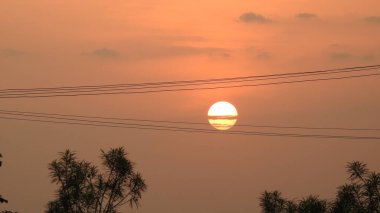 Gölde gün batımında insanların, ağaçların ve teknelerin silueti gün batımında bir arabanın üzerinde dans eden çocukların güzel silueti altın gökyüzü ve siluetli ağaçlar. Çocukların gölgesi parkta birlikte duruyor. Gün batımı gökyüzü ve ağaçlar manzarası.