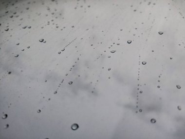 Fırtına sırasında pencere camında büyük yağmur damlaları vardı. Bulutların, yeşil ağaçların ve binaların manzarası. Fırtınalı bir günde yağmur damlalarının şehir manzarası pencereye düşer. Pencereye yağmur damlası. Cama yağmur damlaları. Otomotiv üzerine yağmur damlaları 