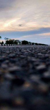 Terk edilmiş asfalt yol ve şafak vakti dağ manzarası, hava yolu asfalt yolu ve güzel gökyüzü manzarası. Güneşli bir yaz gününde ufka giden boş uzun dağ yolu. Gün batımında. Hızlı hareket bulanıklığı etkisi. Asfalt yol ve göl gökyüzü