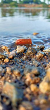 Temiz tatlı suyla nehir yatağındaki kayalar. Deniz suyunda deniz taşları. Suyun altındaki çakıl taşları. Yukarıdan bak. Denizcilik geçmişi. Temiz deniz suyu. Şeffaf deniz. Arka plan gri gri çakıl taşlarından oluşan büyük çakıl taşlarından oluşur. Çakıl taşı 