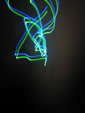 Siyah arkaplandaki ışık şeritlerinden parlak kırmızı spiral desenler. Gece ışığı soyut arka plan, gece ışığı. Mavi ve kırmızı ışık boyama fotoğrafçılık, uzun pozlama peri mavisi ve kırmızı ışıklar kıvrımlar ve dalgalar siyah zemin üzerinde