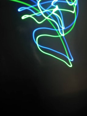 Siyah arkaplandaki ışık şeritlerinden parlak kırmızı spiral desenler. Gece ışığı soyut arka plan, gece ışığı. Mavi ve kırmızı ışık boyama fotoğrafçılık, uzun pozlama peri mavisi ve kırmızı ışıklar kıvrımlar ve dalgalar siyah zemin üzerinde