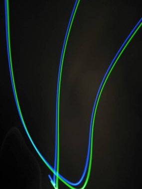 Siyah arkaplandaki ışık şeritlerinden parlak kırmızı spiral desenler. Gece ışığı soyut arka plan, gece ışığı. Mavi ve kırmızı ışık boyama fotoğrafçılık, uzun pozlama peri mavisi ve kırmızı ışıklar kıvrımlar ve dalgalar siyah zemin üzerinde