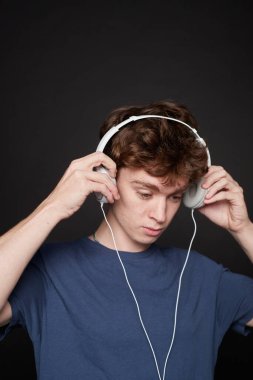 Gri arka planı olan bir fotoğraf stüdyosunda kulaklık takan genç bir adamın yan görüntüsü.